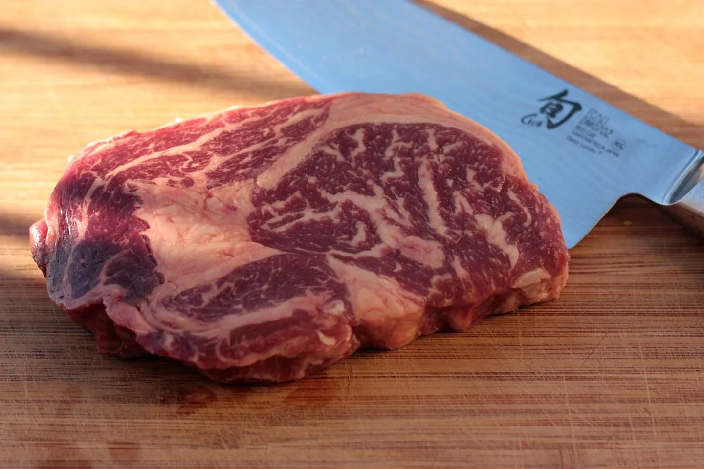 Rohes Black Angus Ribeye mit exzellenter Marmorierung auf Holzbrett
