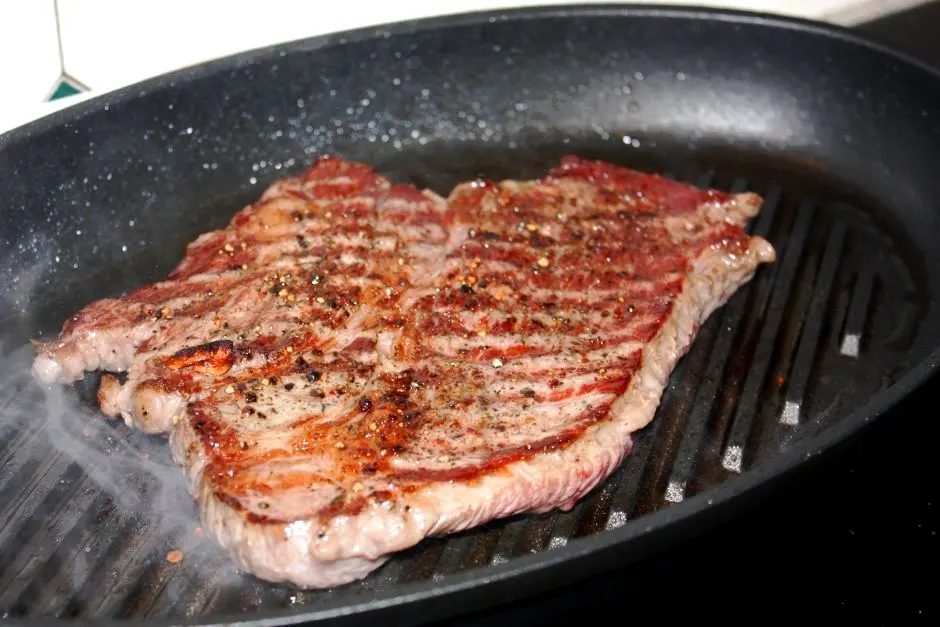 Nackensteak in der Grillpfanne beim Braten mit Röstaromen