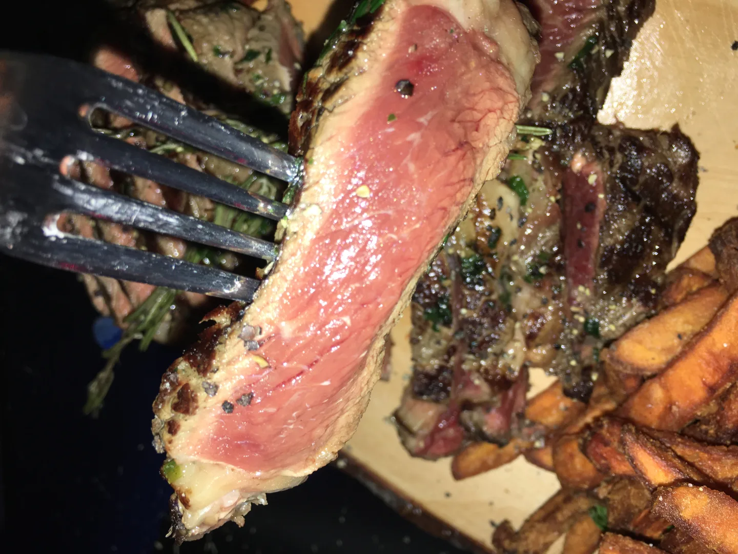 Steak-Anschnitt medium rare mit Kraeuterkruste auf Gabel