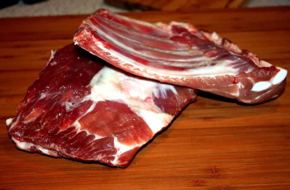 Rohe Spare Ribs auf Holzbrett mit Rub bestreut