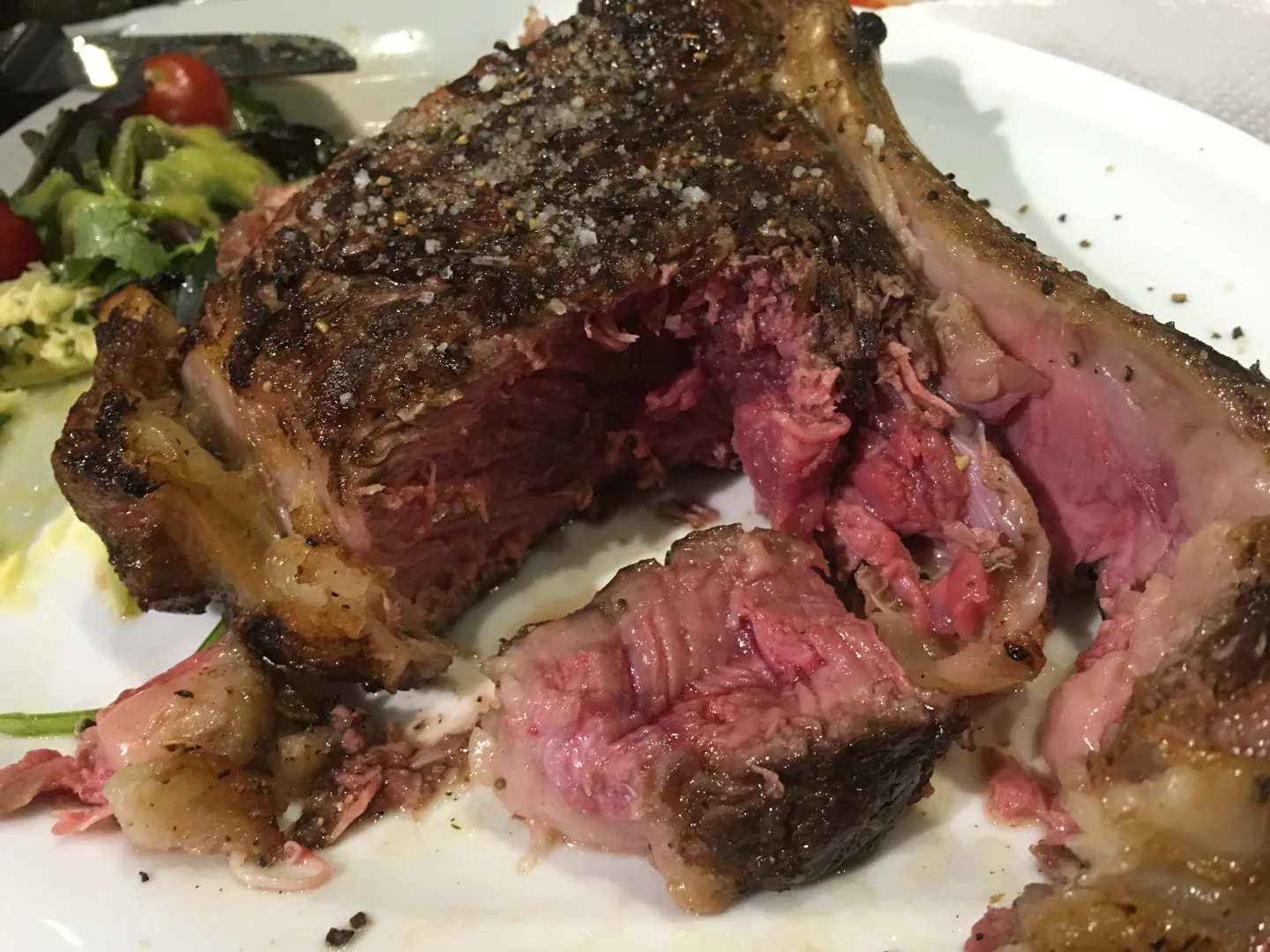 Bone-In-Steak mit Pfefferkruste aufgeschnitten zeigt rosa Kern