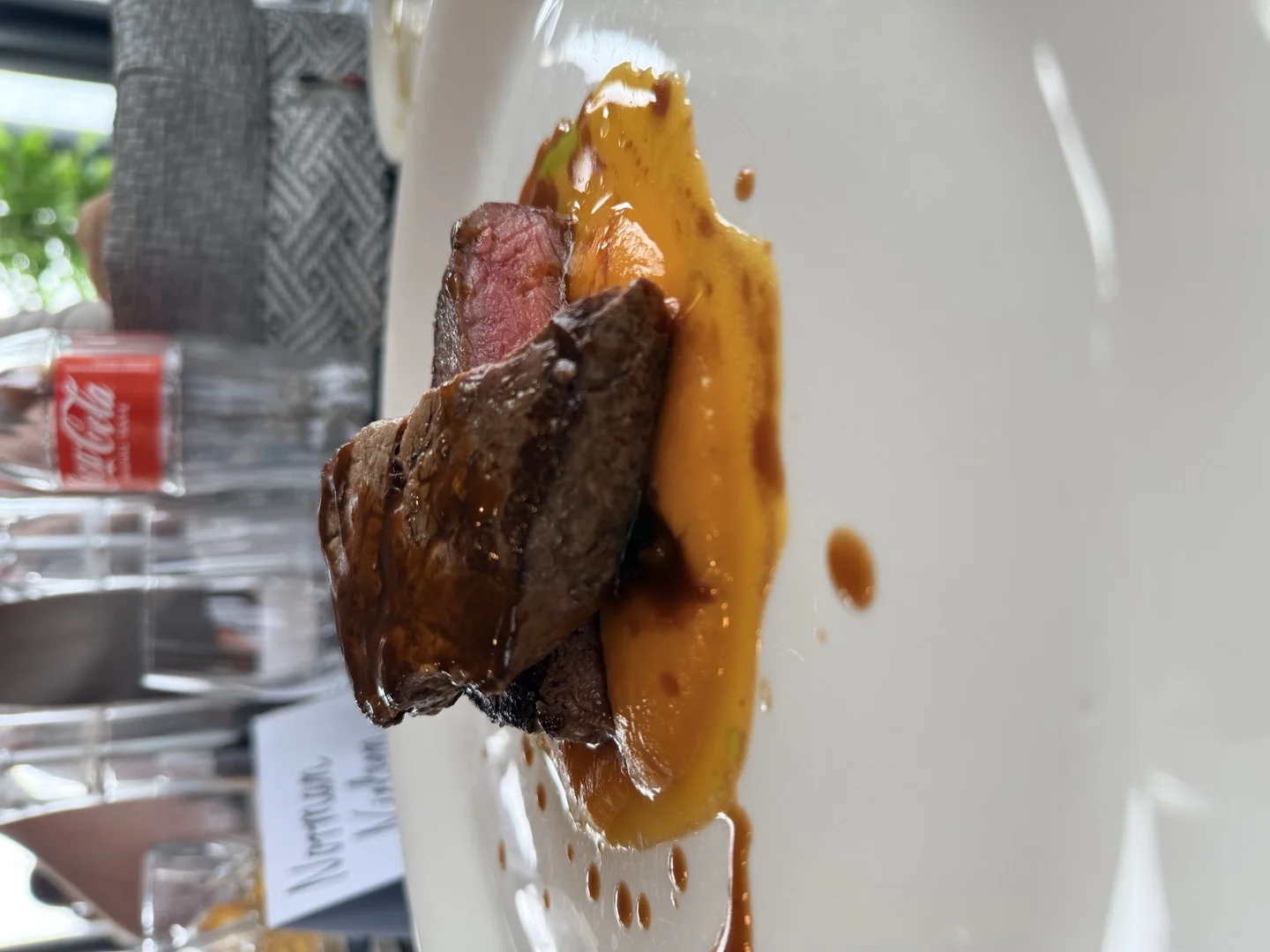 Filet medium rare auf weißem Teller mit Jus im Restaurant mit Norman Nielsen Namensschild im Hintergrund