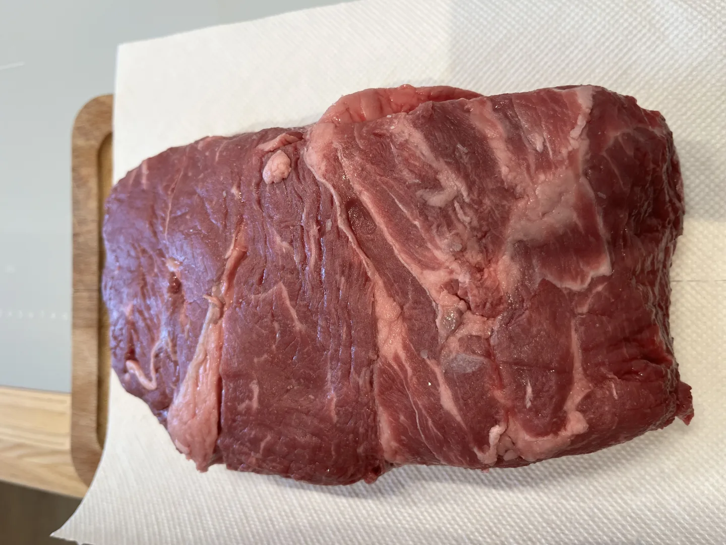 Grosses rohes Fleischstueck mit sichtbarer Faserung auf Schneidebrett