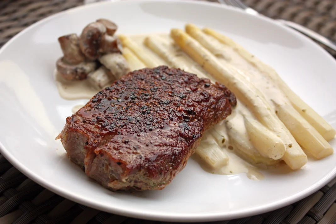 Rumpsteak mit weißem Spargel auf dem Teller angerichtet