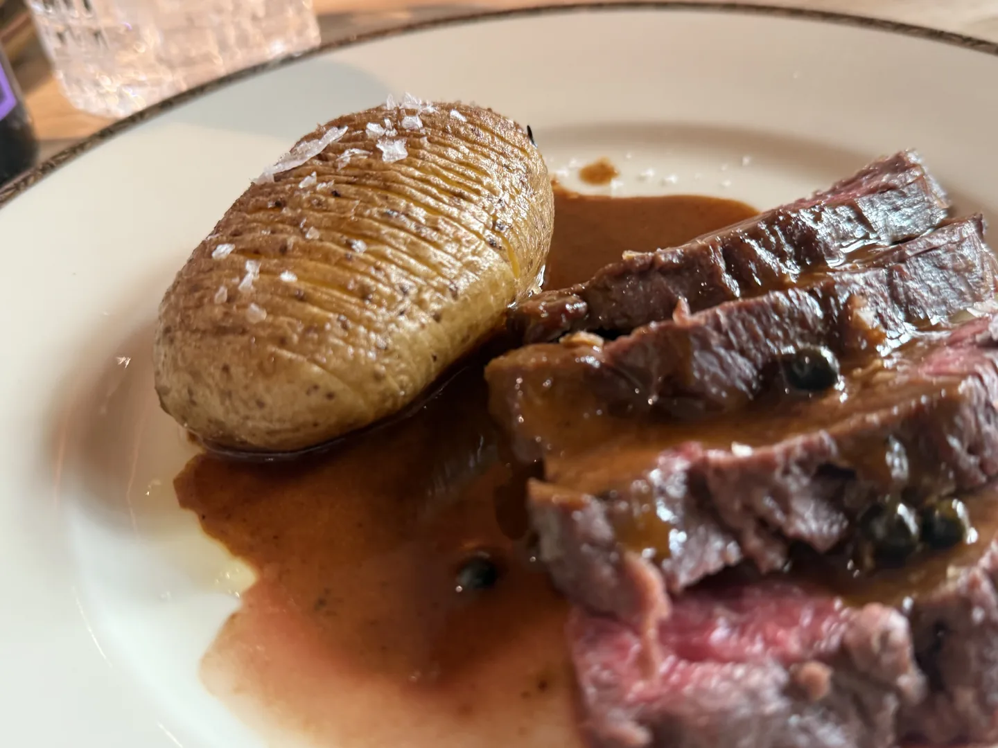 Aufgeschnittenes Steak mit Hasselback-Kartoffel und Pfeffersauce