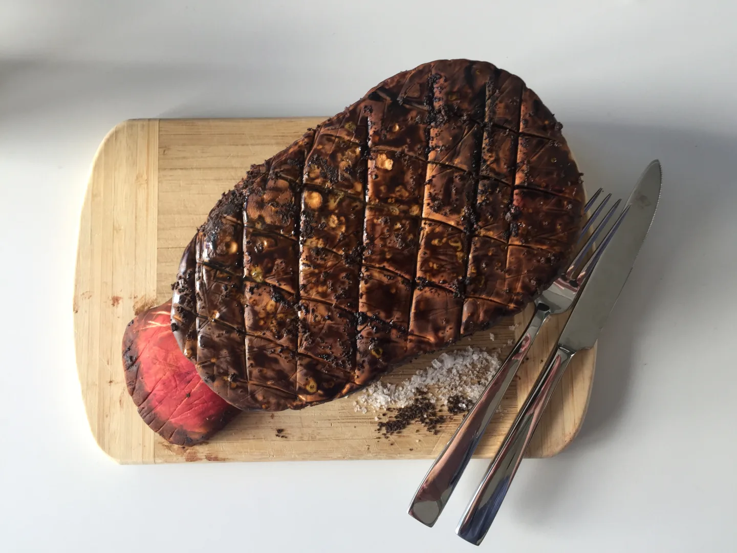 Grosses mariniertes Steak mit Rautenmuster-Einschnitt auf Holzbrett