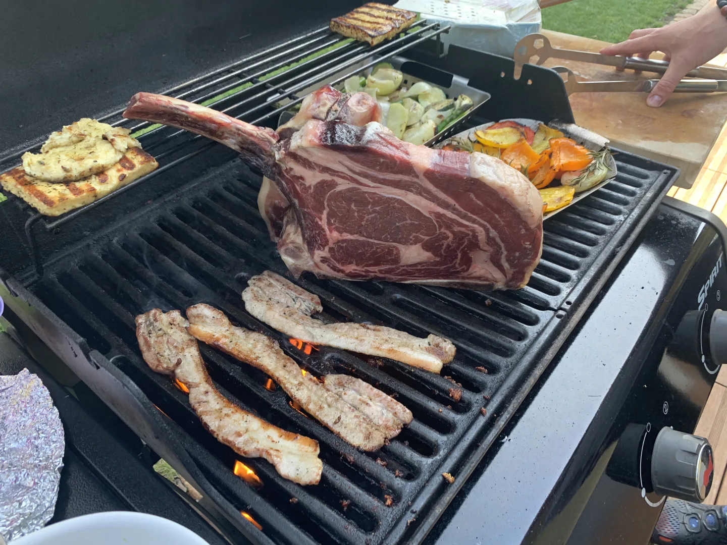 Tomahawk-Steak roh auf Weber-Gasgrill mit Bacon und Grillgemuese